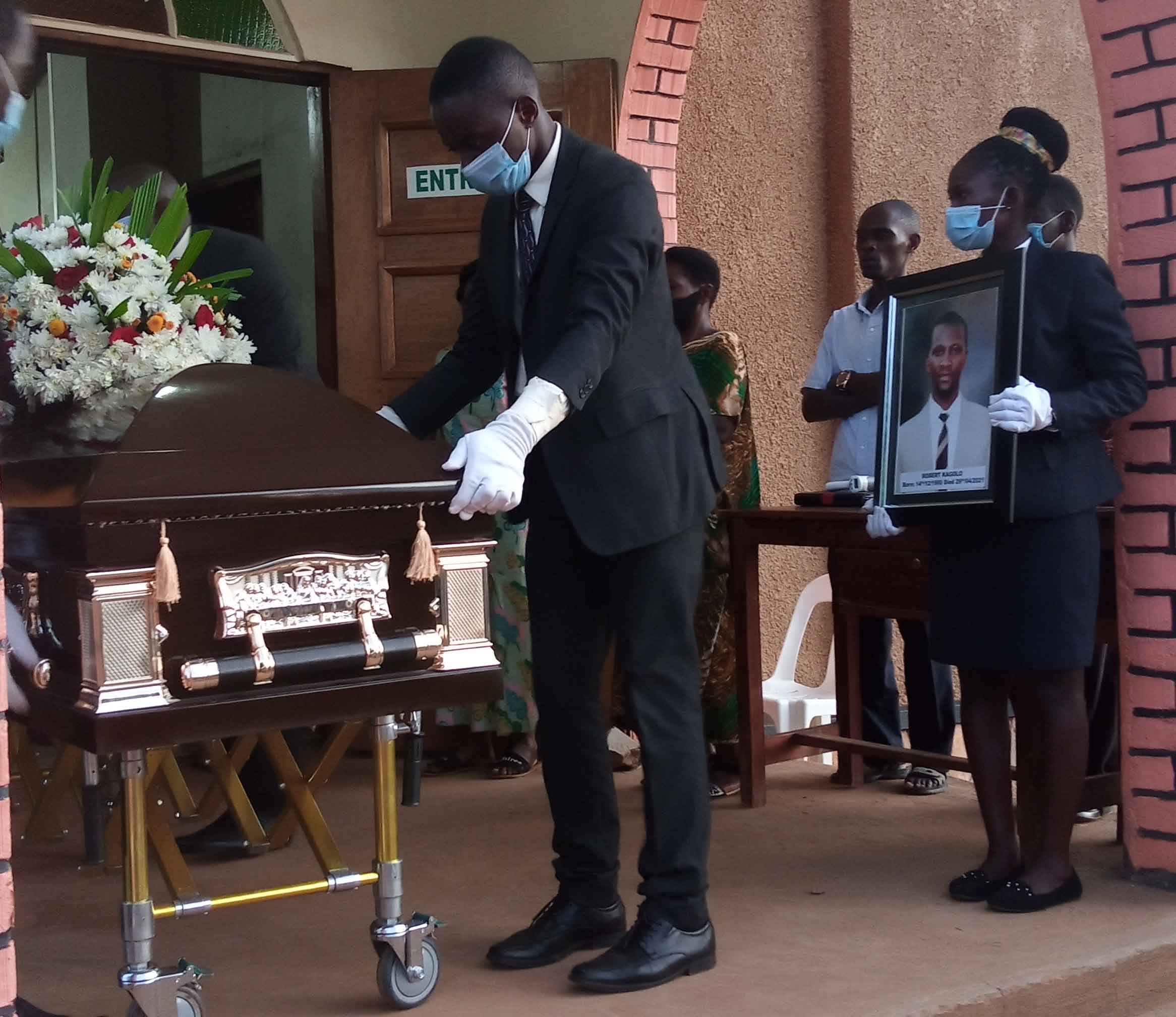Funeral workers prepare the coffin containing the body of Robert Kagolo. Nesday Photo.